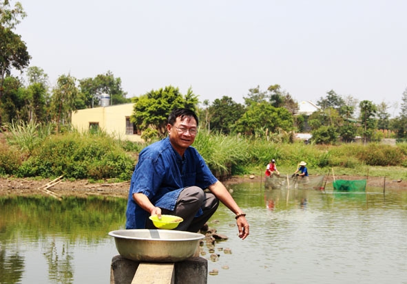 Ông Nguyễn Thanh Bình bên ao cá của gia đình.