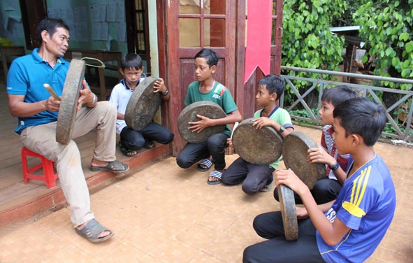 Các em thiếu nhi buôn Hra Ea Hing, xã Dray Bhang (huyện Cư Kuin) học đánh cồng chiêng tại nhà cộng đồng.   Ảnh: Hoàng Gia