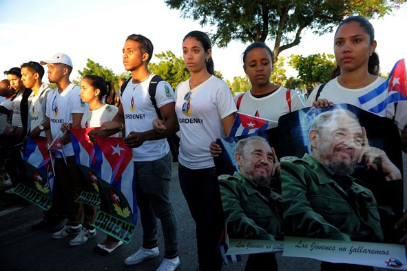 Thanh niên Cuba cầm ảnh chân dung lãnh tụ Fidel Castro dọc tuyến đường  dẫn đến nghĩa trang Santa Ifigenia. (Nguồn: AFP)