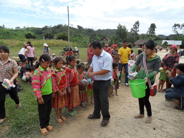 Ông Nguyễn Văn Tâm (áo trắng) tặng quà cho học sinh trường Tiểu học Cư Pui 2.