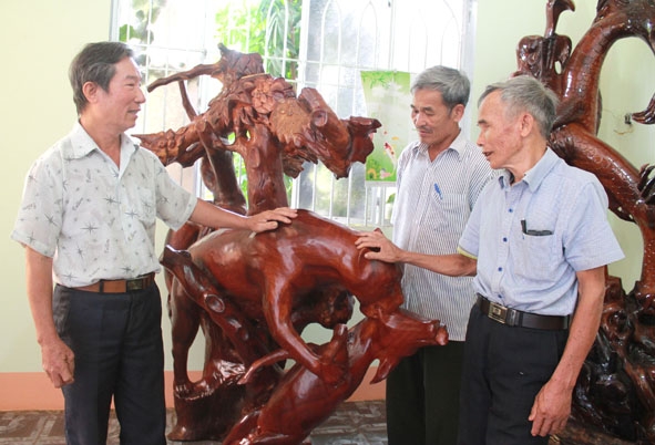 Thương binh Lê Văn Thuần (bên trái) giới thiệu các tác phẩm điêu khắc gỗ với cán bộ, hội viên người cao tuổi.