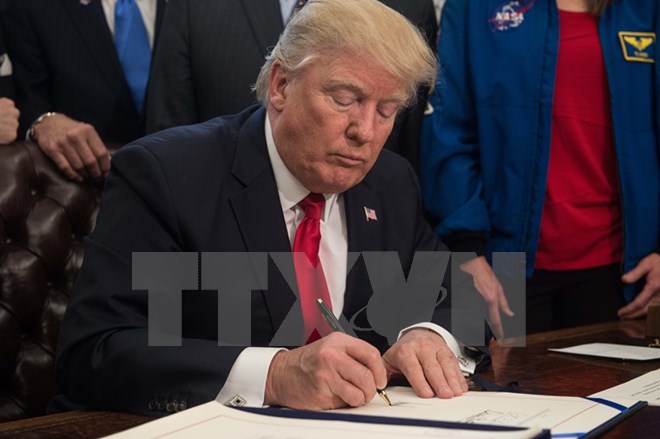 Tổng thống Mỹ Donald Trump ký ban hành một đạo luật tại Nhà Trắng ngày 21-3. (Ảnh: AFP/TTXVN)