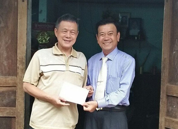 Chủ tịch UBND huyện Cư Kuin Nguyễn  Năng Chung (bên phải) thăm hỏi  và tặng quà  một gia đình chính sách trên địa bàn. 