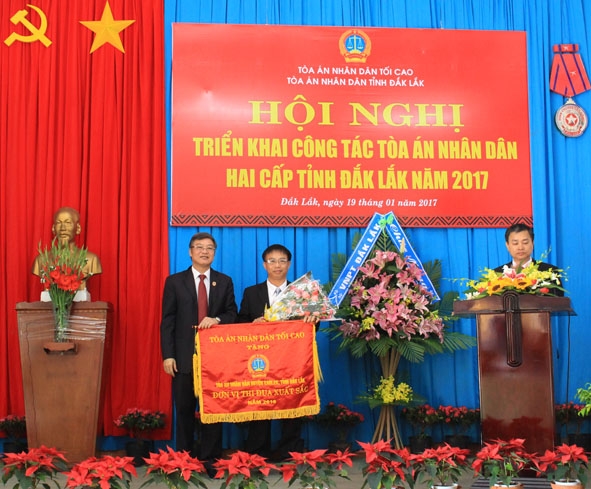 Phó Chánh án TAND Tối cao Nguyễn Sơn (bìa trái) trao Cờ Thi đua của TAND Tối cao tặng TAND huyện Ea H'leo vì có thành tích trong năm 2016. 