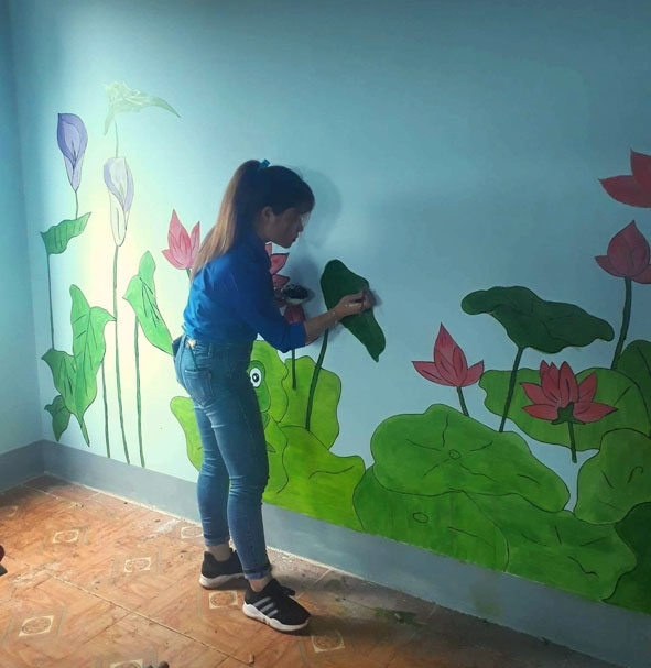 Thành viên Đội công tác xã hội huyện Cư M'gar sơn vẽ lại tường cho lớp học  ở buôn H'Mông (xã Ea Kiết). 