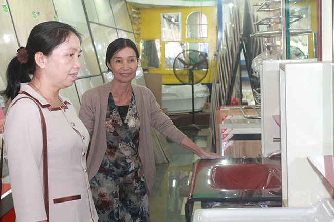 Bà Ngô Thị Ngọc Lan (bên phải) giới thiệu các sản phẩm trang trí nội thất tại cửa hàng của gia đình.   
