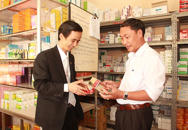 Anh Phan Thành Trinh, Tổng Giám đốc Công ty Cổ phần Dược – Vật tư y tế Đắk Lắk (bìa trái) kiểm tra các sản phẩm thuốc của đơn vị được trưng bày tại cửa hàng.