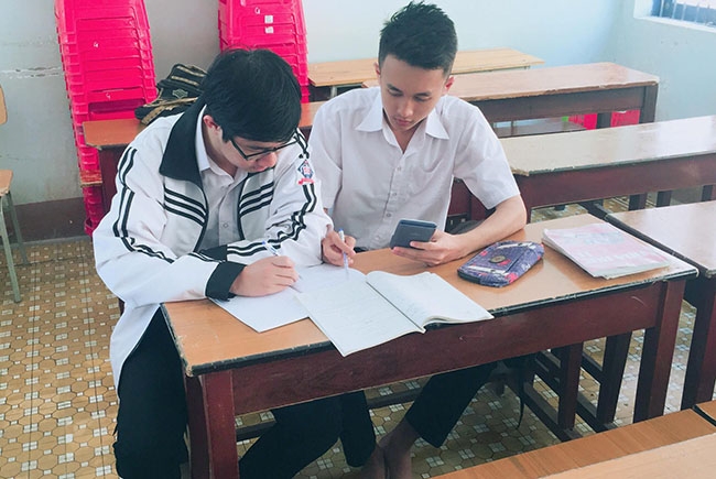 Em Nguyễn Nhật Minh (phải) trao đổi bài với bạn trong giờ giải lao  giữa  buổi học.  