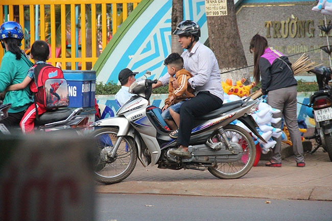 Phụ huynh một tay lái xe, một tay giữ con nhỏ trước bụng di chuyển trên tuyến đường Phan Chu Trinh (TP. Buôn Ma Thuột).