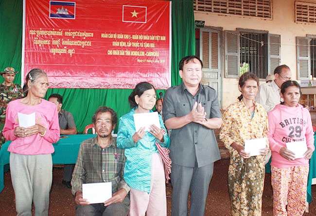 Cán bộ Bộ CHQS tỉnh Đắk Lắk tặng quà và sổ tiết kiệm cho người dân nghèo xã Pu Ch’ri, huyện Bét Chăn Đa, tỉnh Mundulkiri (Campuchia).