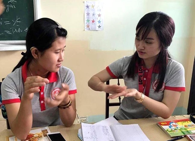 Nguyễn Thị Hoài Phương (bên phải) truyền đạt ngôn ngữ  ký hiệu  cho các bạn  trong  Câu lạc bộ Thanh niên khuyết tật tỉnh.