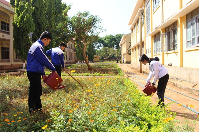 Các em học sinh chăm sóc bồn hoa, cây cảnh trong khuôn viên nhà trường. 
