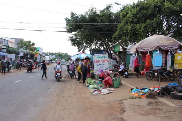 Người dân vô tư lấn chiếm lề đường trước chợ 19-8 (xã Ea Tiêu, huyện Cư Kuin) để buôn bán.