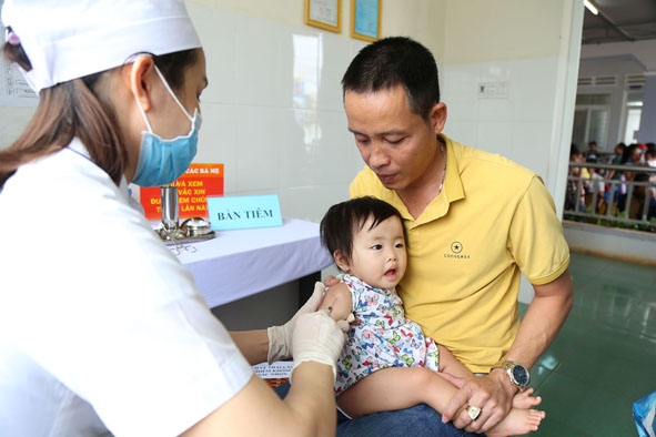 Phụ huynh đưa trẻ đi tiêm phòng tại Trạm Y tế phường Tân An (TP. Buôn Ma Thuột). 