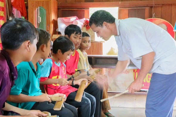 Nghệ nhân Y Goh Niê hướng dẫn các em thiếu nhi buôn Kram (xã Ea Tiêu, huyện Cư Kuin)  học đánh chiêng.   