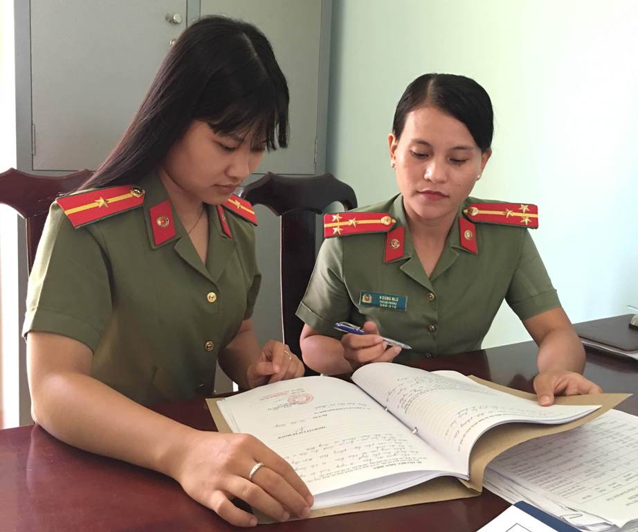 Thượng úy HDũng Mlô (phải), Phó đội trưởng Đội An ninh - Công an huyện MĐrắk  đang trao đổi công việc với đồng nghiệp.