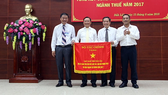 Phó Chủ tịch UBND tỉnh Y Giang Gry Niê Knơng (ngoài cùng bên phải) trao tặng Cờ thi đua của Bộ Tài chính cho Cục thuế tỉnh.