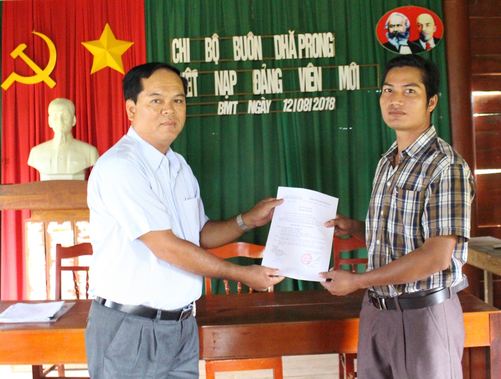 Đồng chí Trịnh Duy, Bí thư Chi bộ buôn Dhă Prông trao Quyết định kết nạp Đảng cho đảng viên trẻ Y Đông Niê.  