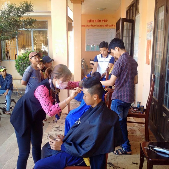 Các thành viên CLB “Kết nối bốn phương” cắt tóc cho thiếu niên xã Cư Huê.  