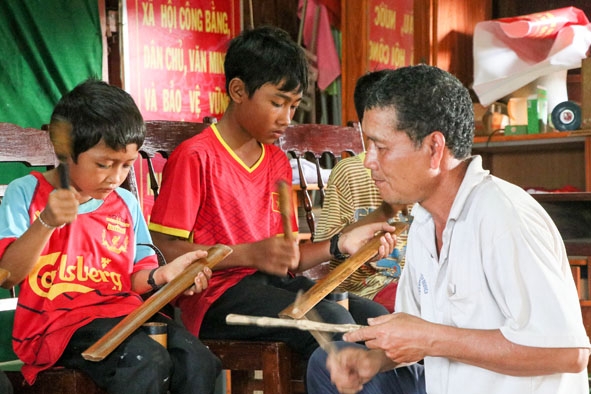 Nghệ nhân Y Goh Niê hướng dẫn các em thiếu nhi buôn Kram, xã Ea Tiêu (huyện Cư Kuin) cách đánh chiêng.    Ảnh: N.Gia