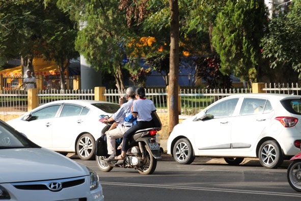 Phụ huynh chở con em trên xe gắn máy nhưng không đội mũ bảo hiểm.  (Ảnh chụp trên đường Phan Bội Châu, TP. Buôn Ma Thuột).
