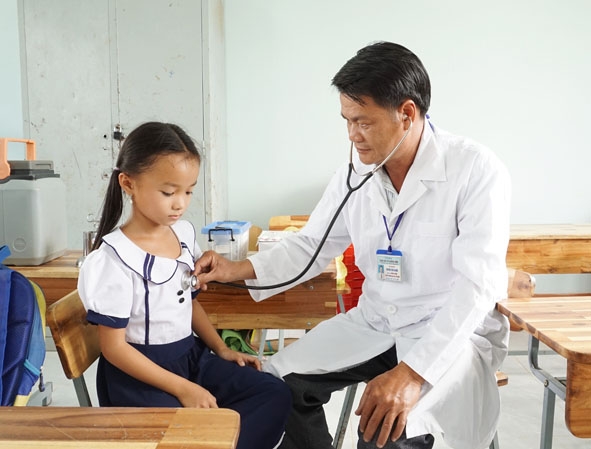 Bác sĩ Trung tâm Y tế huyện Krông Bông khám sàng lọc trước khi tiêm vắc xin  cho trẻ em xã Cư Pui. 