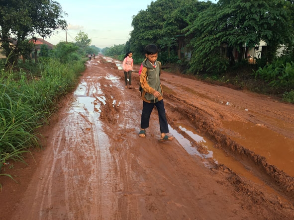 Các em học sinh ở xã Cư Amung vất vả đi học trên con đường đất lầy lội vào mùa mưa.  