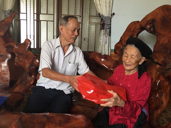 Ông Bùi Văn Lết (trái), Chủ tịch Hội NCT xã Cư Mta tặng quà mừng thọ cụ Nguyễn Thị Hỉ tròn 100 tuổi. 