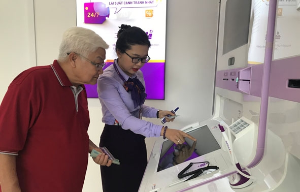 Nhân viên TPBank Đắk Lắk hỗ trợ một khách hàng lớn tuổi gửi tiết kiêm qua LiveBank. 