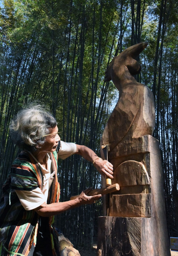 Nghệ nhân Bhriu Pố đang hoàn thiện bức tượng Gà trống tham dự cuộc thi Điêu khắc gỗ dân gian. 