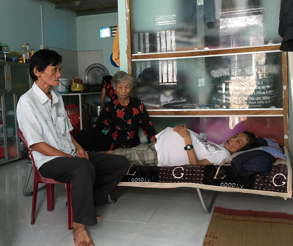 Vợ chồng bà Nguyễn Thị Vương (tổ dân phố 10, thị trấn M'Đrắk, huyện M'Đrắk) bên người con trai đang bệnh nặng.