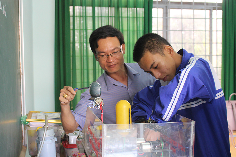 Em Vũ Thanh Sơn (phải),  Trường THPT  Y Jút  cùng với thầy giáo nghiên cứu một sản phẩm khoa học.