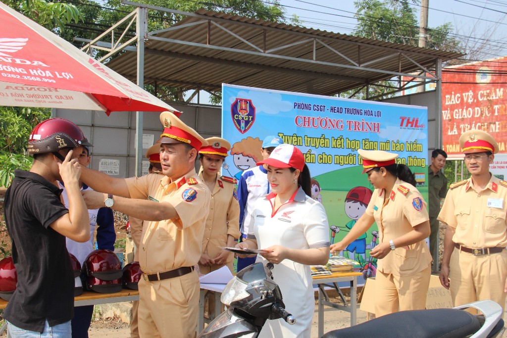 Trung tá Huỳnh Thanh Bình, Phó trưởng Phòng CSGT (Công an tỉnh) tặng mũ bảo hiểm cho người dân.
