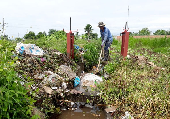 Ông Dương Tấn Khanh (thôn 3, xã Hòa Phú) phải túc trực để khơi thông rác, tránh tắc nghẽn làm nước tràn vào vườn nhà.