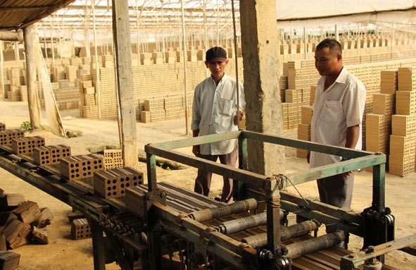 Ông Nguyễn Văn Vui (bìa trái) kiểm tra tình hình hoạt động của một cơ sở sản xuất gạch  trực thuộc Hợp tác xã công nghiệp Ea Uy. 