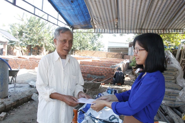 Đại diện Ban Tuyên giáo Huyện ủy Krông Ana trao tiền hỗ trợ làm nhà cho gia đình ông Nguyễn Minh Tự. 