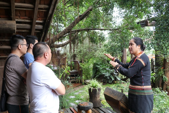 Chủ quán cà phê Arul, buôn Akô Dhông  (TP. Buôn Ma Thuột)  giới thiệu với du khách về nét  độc đáo của văn hóa Êđê.  Ảnh: H. Gia