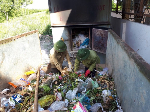 Công nhân vệ sinh môi trường ở chợ Ea Rốk đang cho rác vào lò đốt.