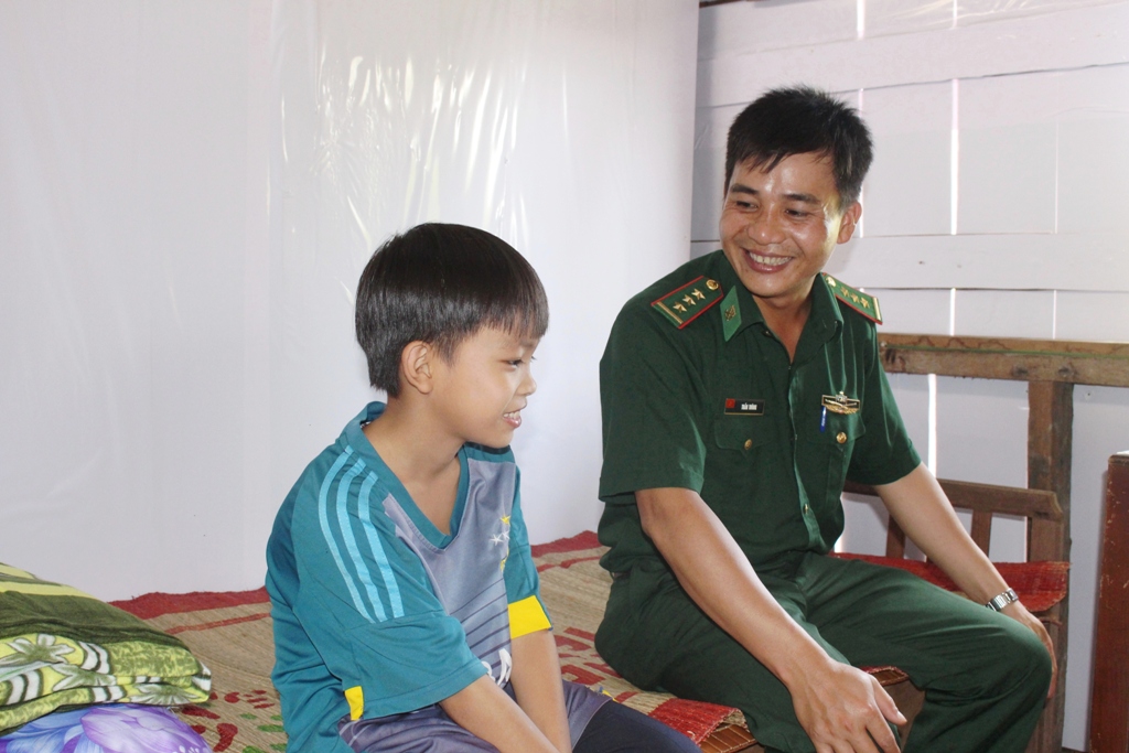 Cán bộ  Đồn Biên phòng Cửa khẩu Đắk Ruê chuyện trò  cùng con nuôi  của Đồn -  cháu Phạm Vũ Đình Hiếu. 
