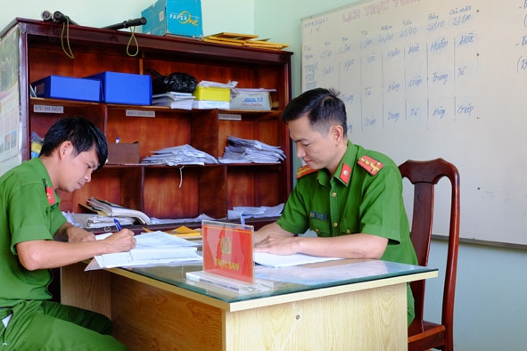 Đại úy Mai Văn Hòa, Trưởng Công an xã Cư Êbur, TP. Buôn Ma Thuột (bên phải) xử lý hồ sơ tại trụ sở làm việc. 