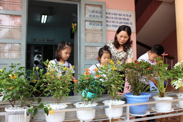 Học sinh Trường Tiểu học Nguyễn Công Trứ chăm sóc cây xanh trước hành lang lớp học. 