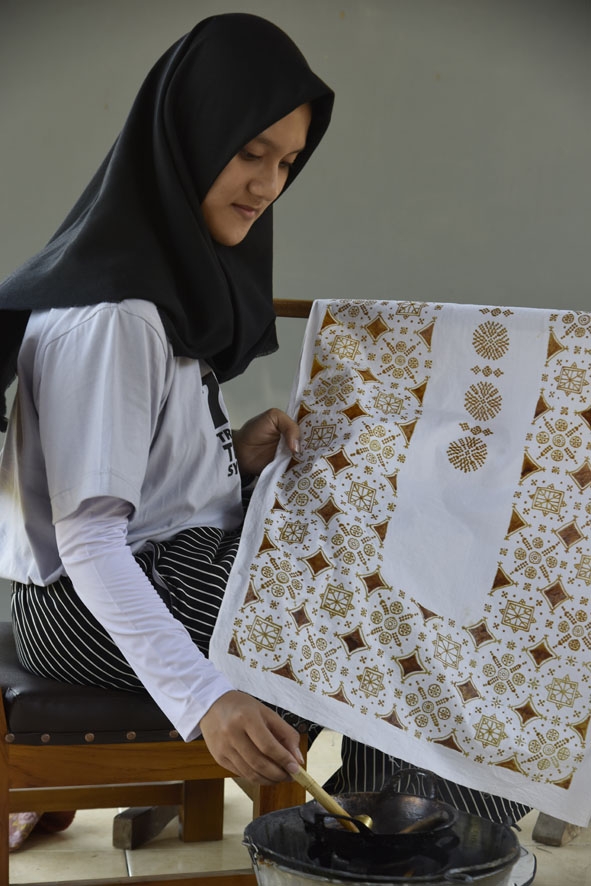 Vẽ sáp ong trên vải để tạo hoa văn batik.  