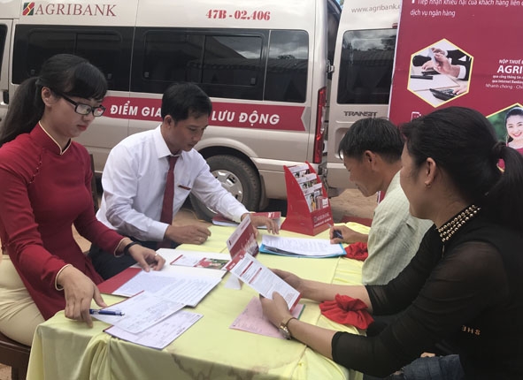 Khách hàng sử dụng dịch vụ ngân hàng lưu động bằng xe ô tô chuyên dùng của Agribank tại huyện Ea  H'leo. 