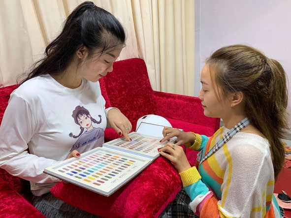  Chị Vương  Thu Hương  (bên phải)  tư vấn  các màu sơn  cho khách hàng lựa chọn. 