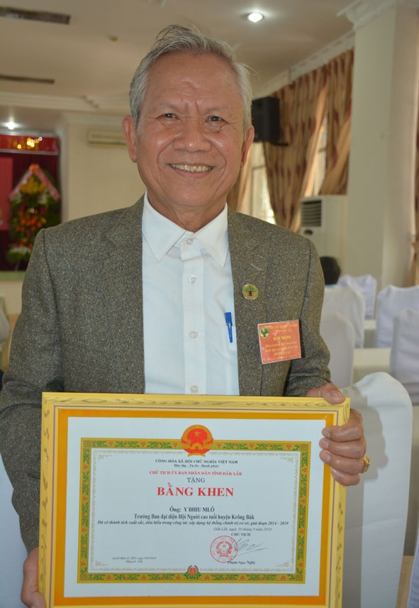 Ông Y Bhiu Mlô nhận Bằng khen của UBND tỉnh tại Hội nghị biểu dương người cao tuổi tham gia xây dựng hệ thống chính trị cơ sở giai đoạn 2014 - 2019.  