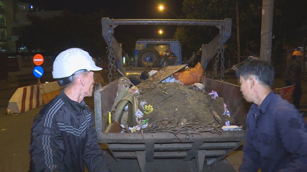Công nhân vệ sinh  chất rác  lên xe chuyên dụng  trong đêm giao thừa.    