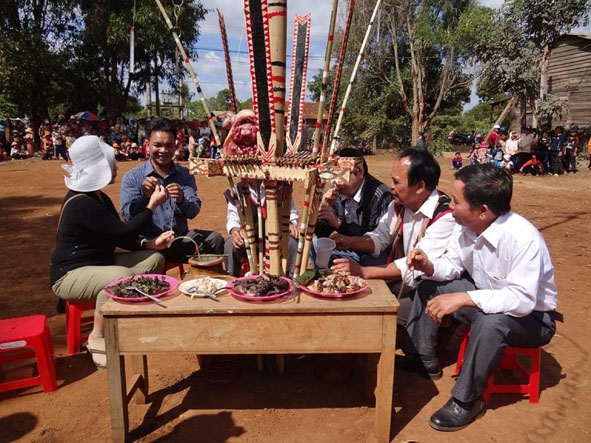 Ông A Nít (thứ hai từ phải sang) trò chuyện với khách dự Lễ hội mừng lúa mới của buôn Hring. 