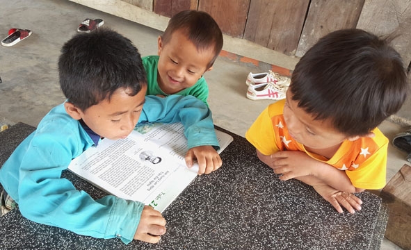 Em Thào  Văn Thành  (bìa trái) dân tộc Hmông, học sinh lớp 4A Trường Tiểu học Ea Bar, xã Cư Pui ôn bài ở nhà. 