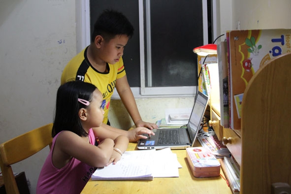  Em Lê Thị Bảo Ngọc,  lớp 1B, trường Tiểu học Ngô Quyền (TP. Buôn Ma Thuột)  học trực tuyến  với sự giúp đỡ  của anh trai. 