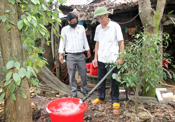 Cán bộ xã Ea Sar (huyện Ea Kar) khảo sát nguồn nước sinh hoạt của gia đình ông Lê Quang Bình  (bên phải). 